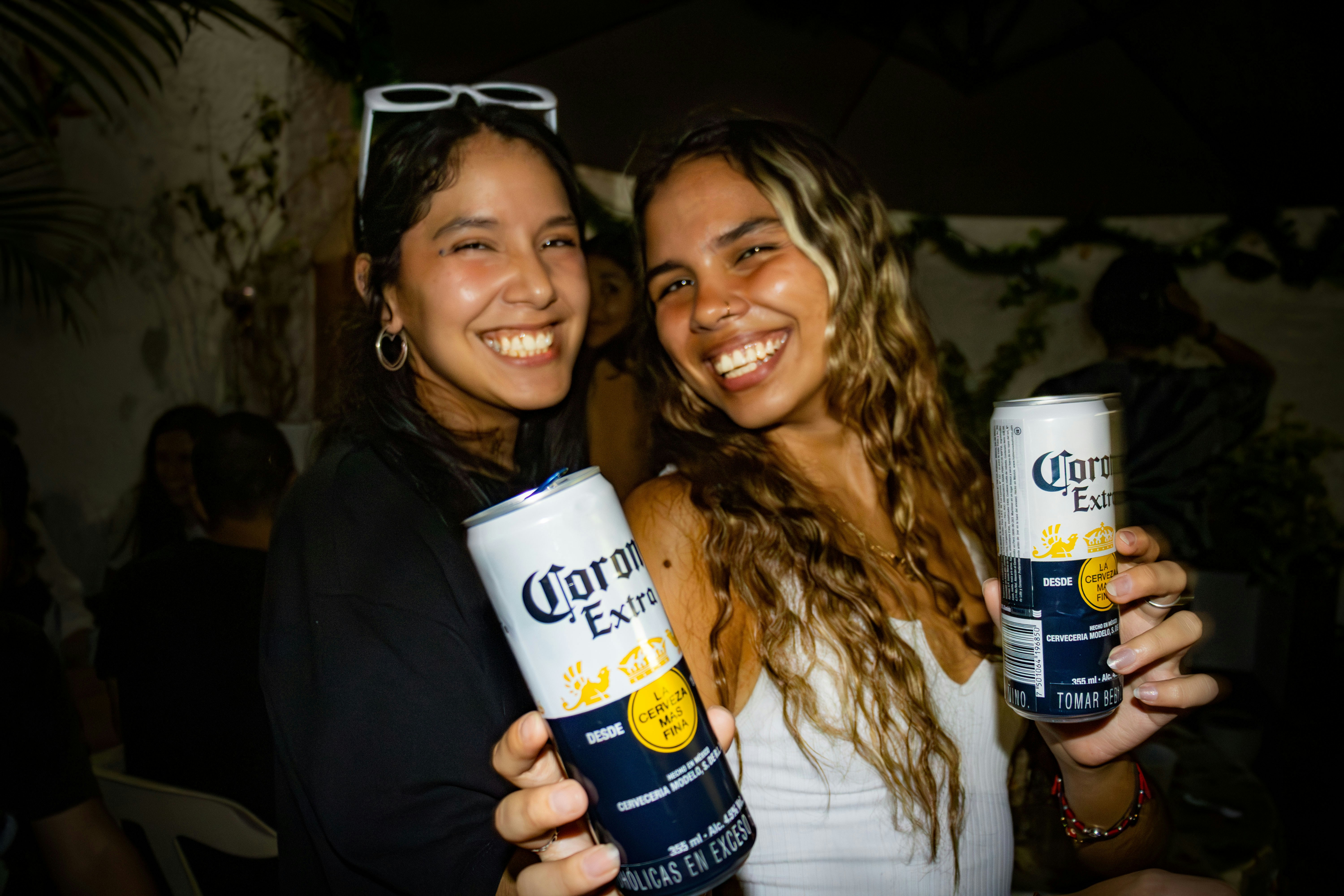 two women holding cans of corona energy drink