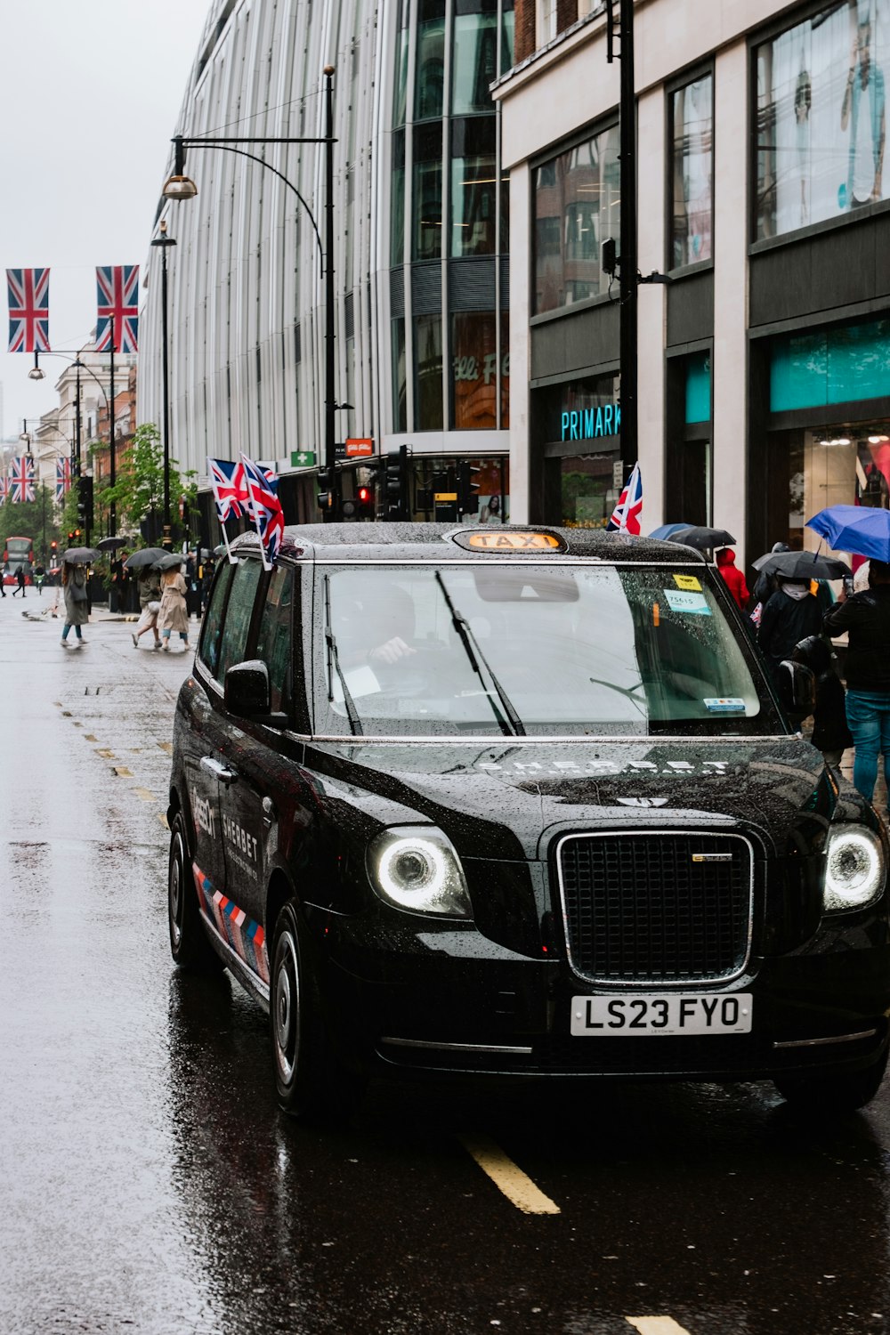 a black car driving down a street next to tall buildings