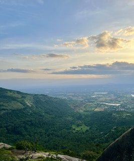 Panoramic view from the camp showing lush green mountain ranges beneath a pastel sunset sky.