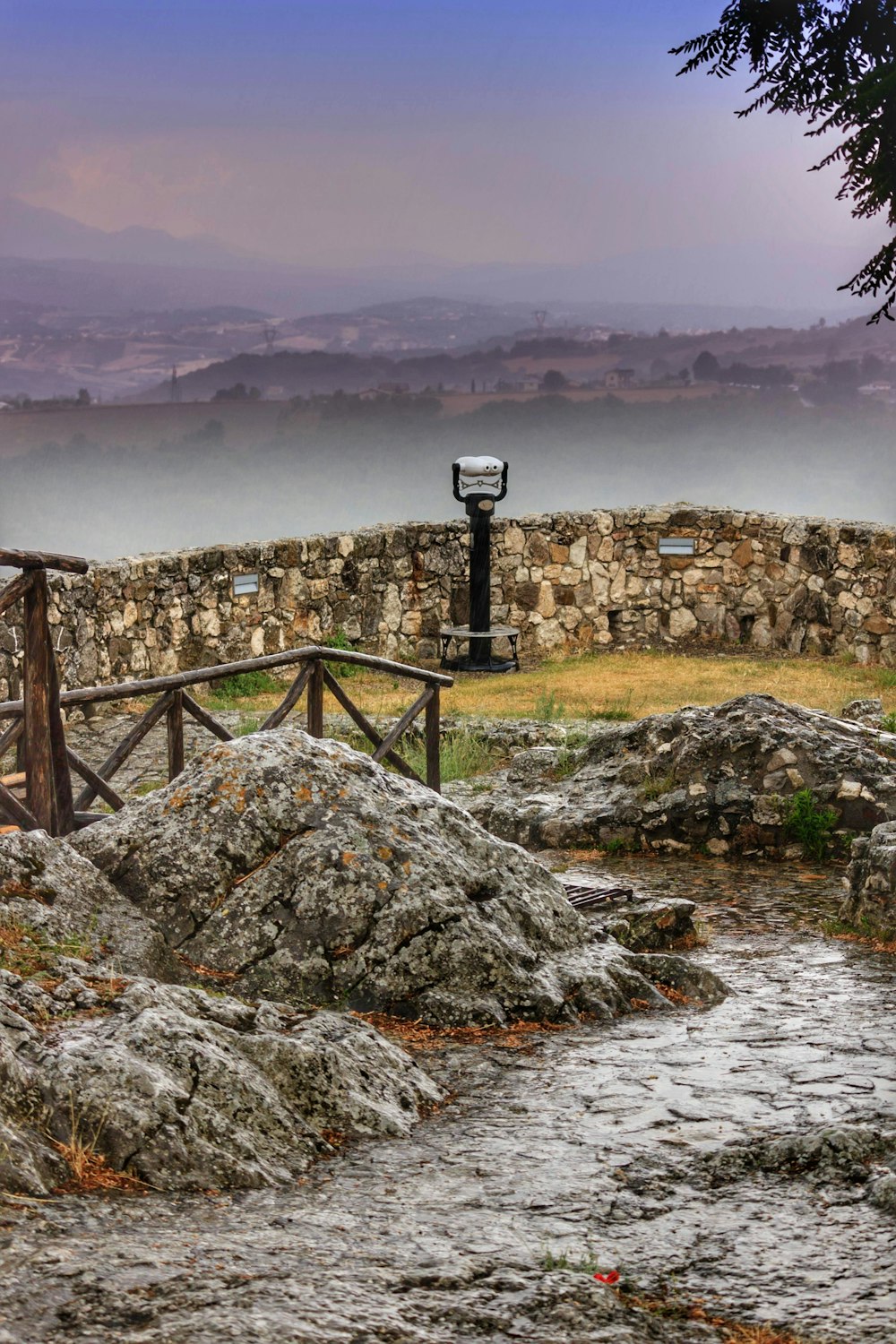 a stone wall with a wooden gate and a light pole