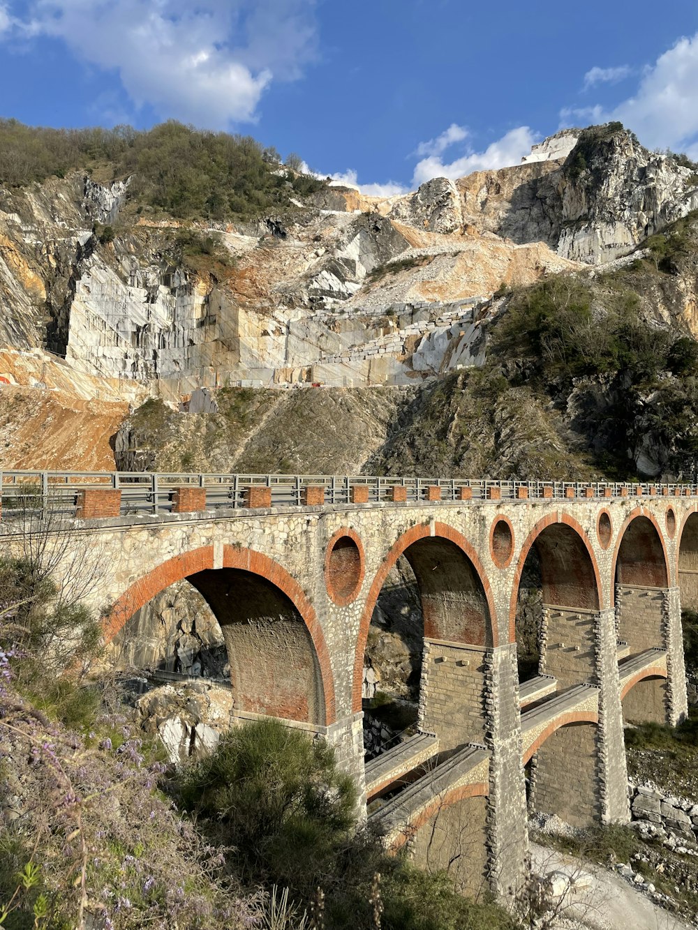 a stone bridge over a river with a mountain in the background