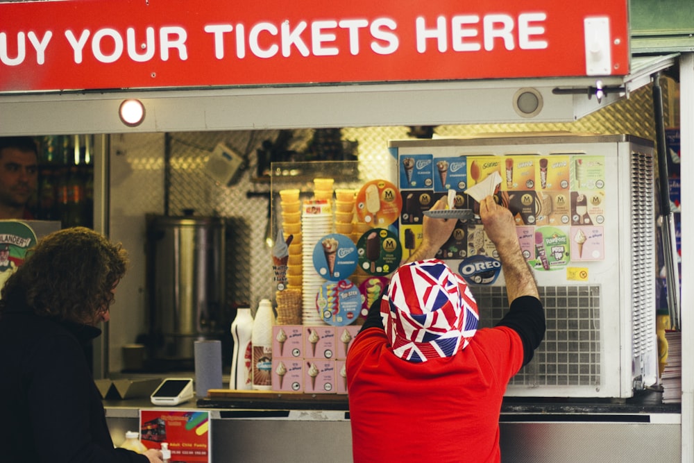 a person in a red hoodie at a ticket booth