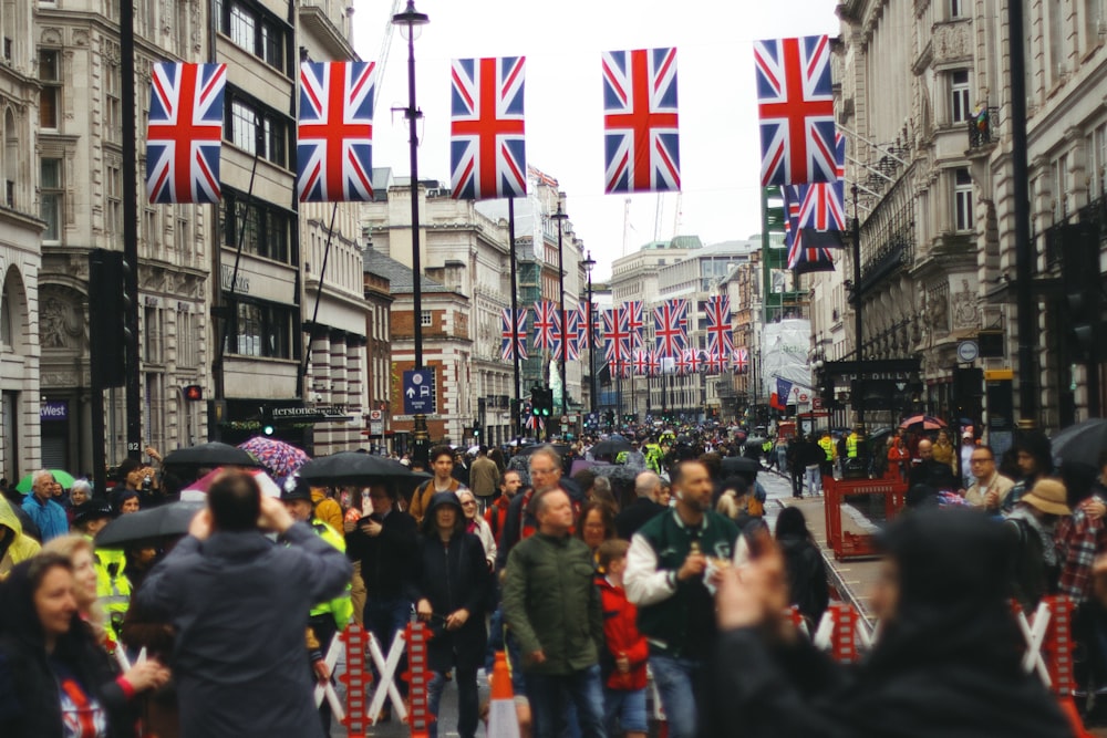 a crowd of people walking down a street holding umbrellas