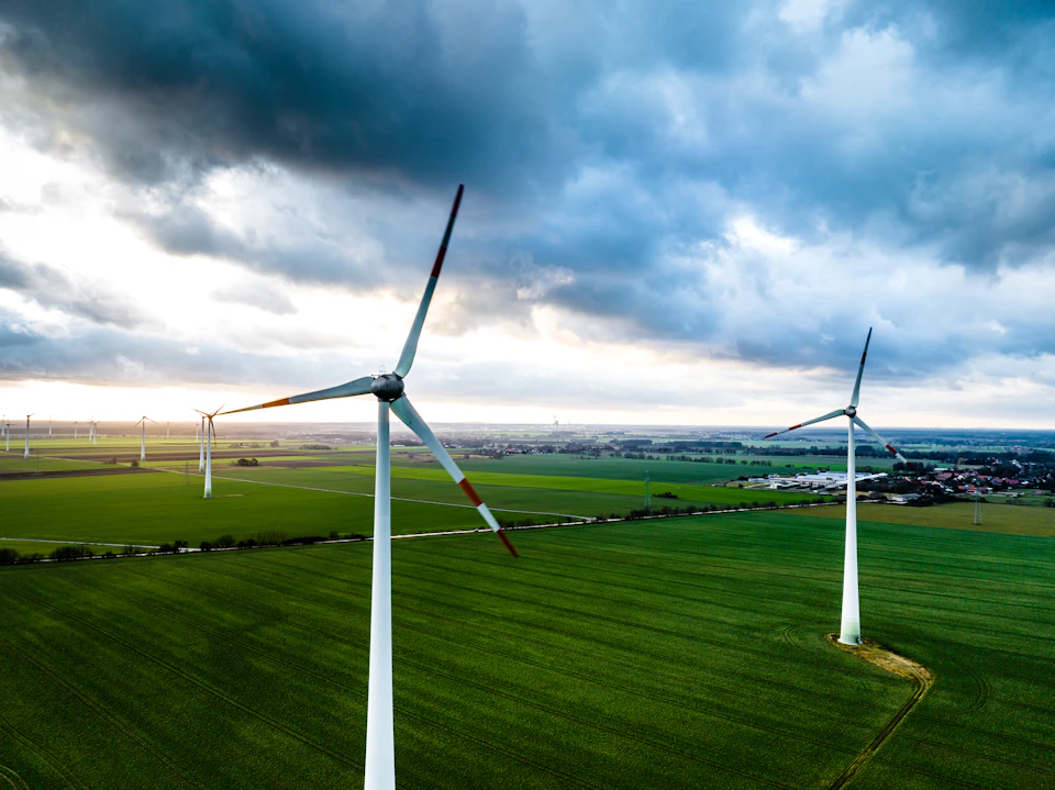 Four white wind turbines stand tall against a cloudy sky with varying designs