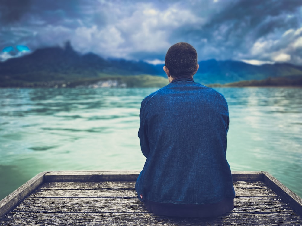 a man sitting on a dock looking at the water