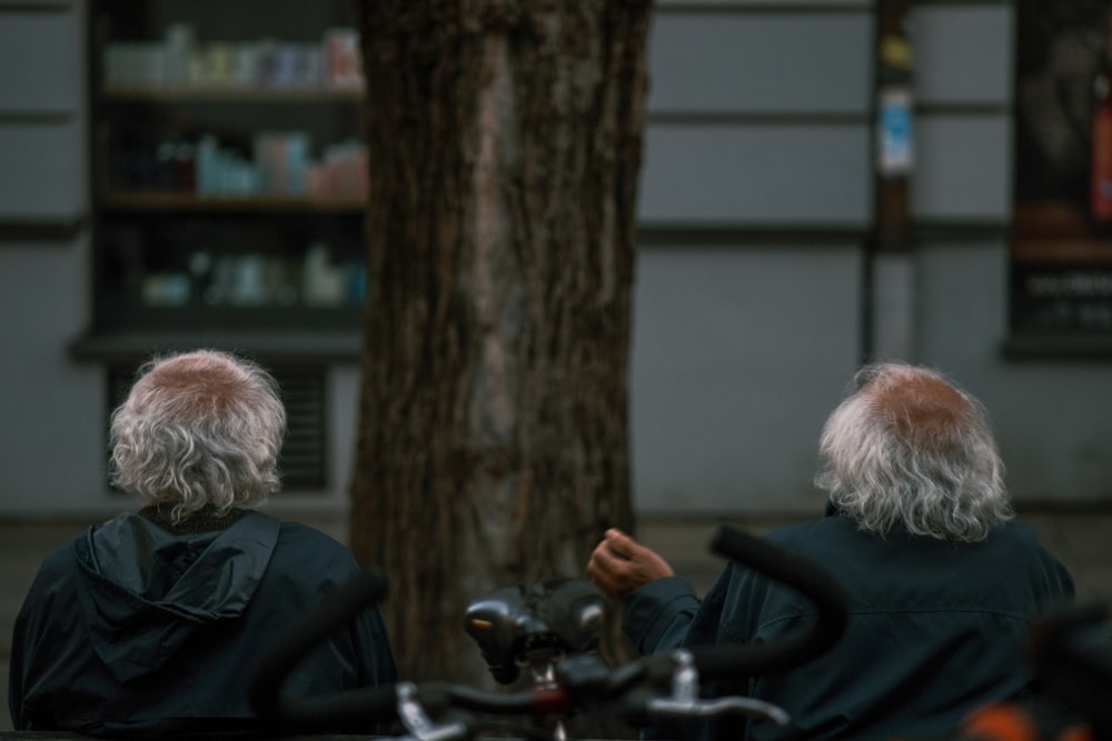 a couple of people sitting next to a tree