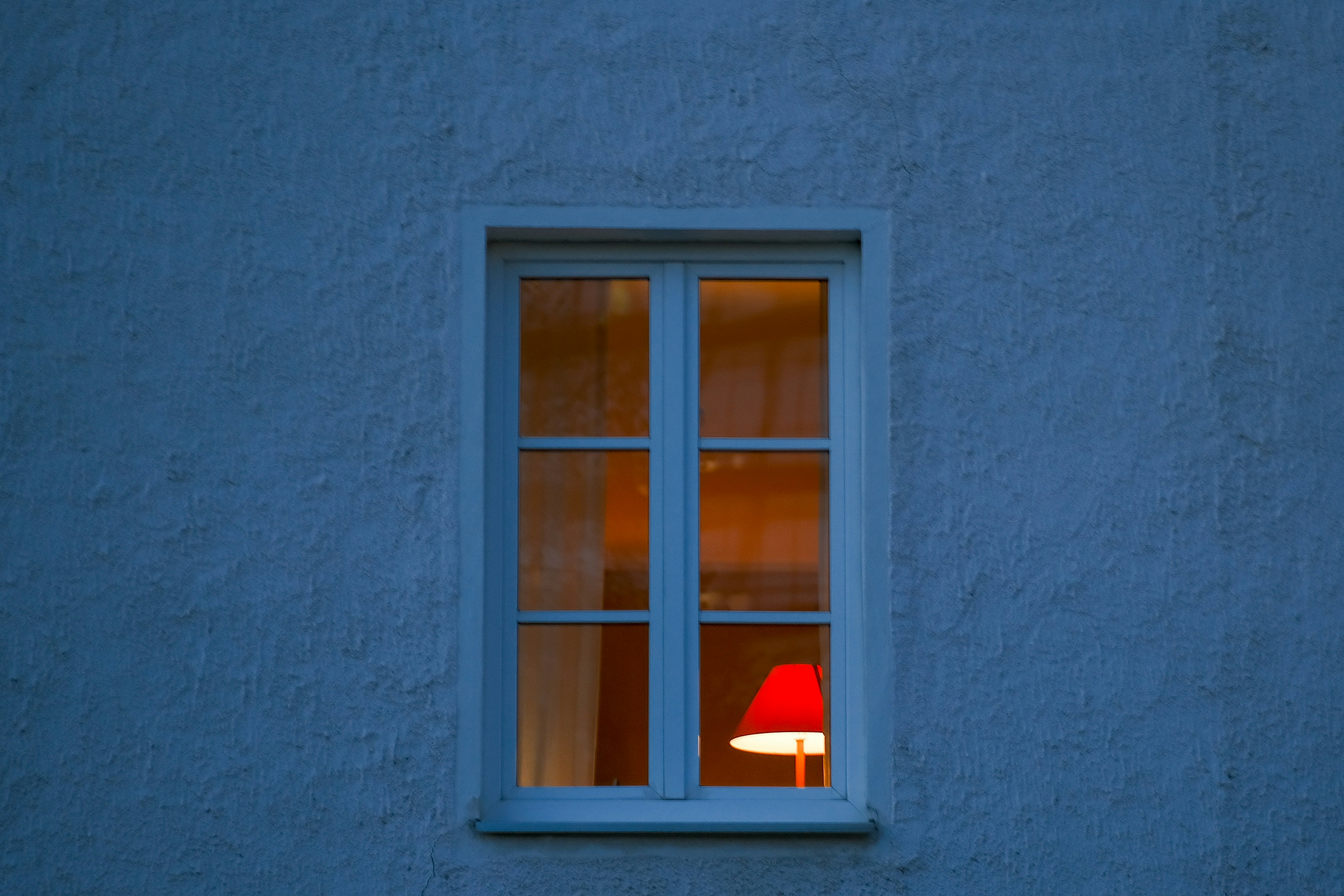 a red lamp sitting in a window next to a blue wall