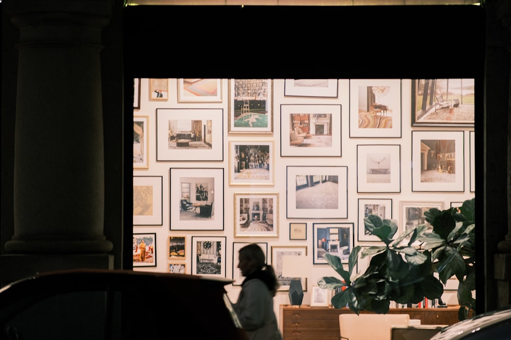 a woman standing in front of a wall covered in pictures