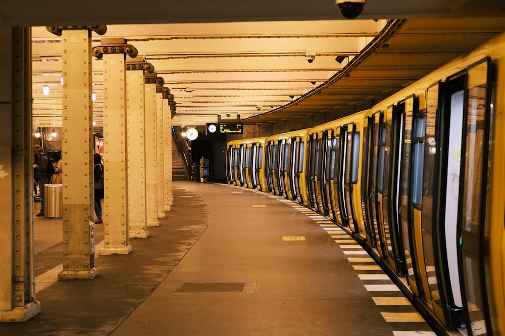 Una estación de metro con un tren amarillo estacionado al lado