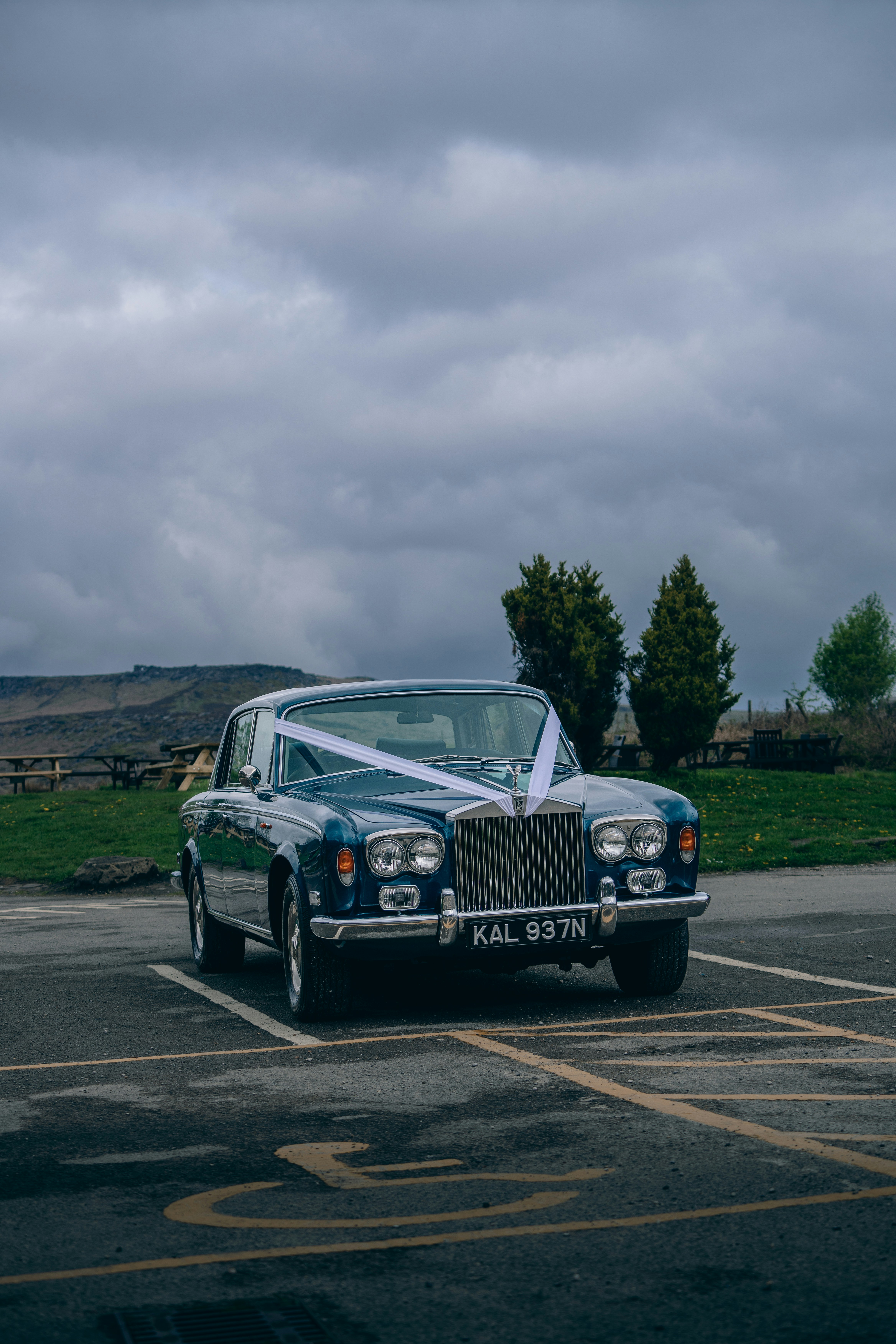 White Rolls Royce classic car on grey road, overcast sky, timeless British luxury automobile
