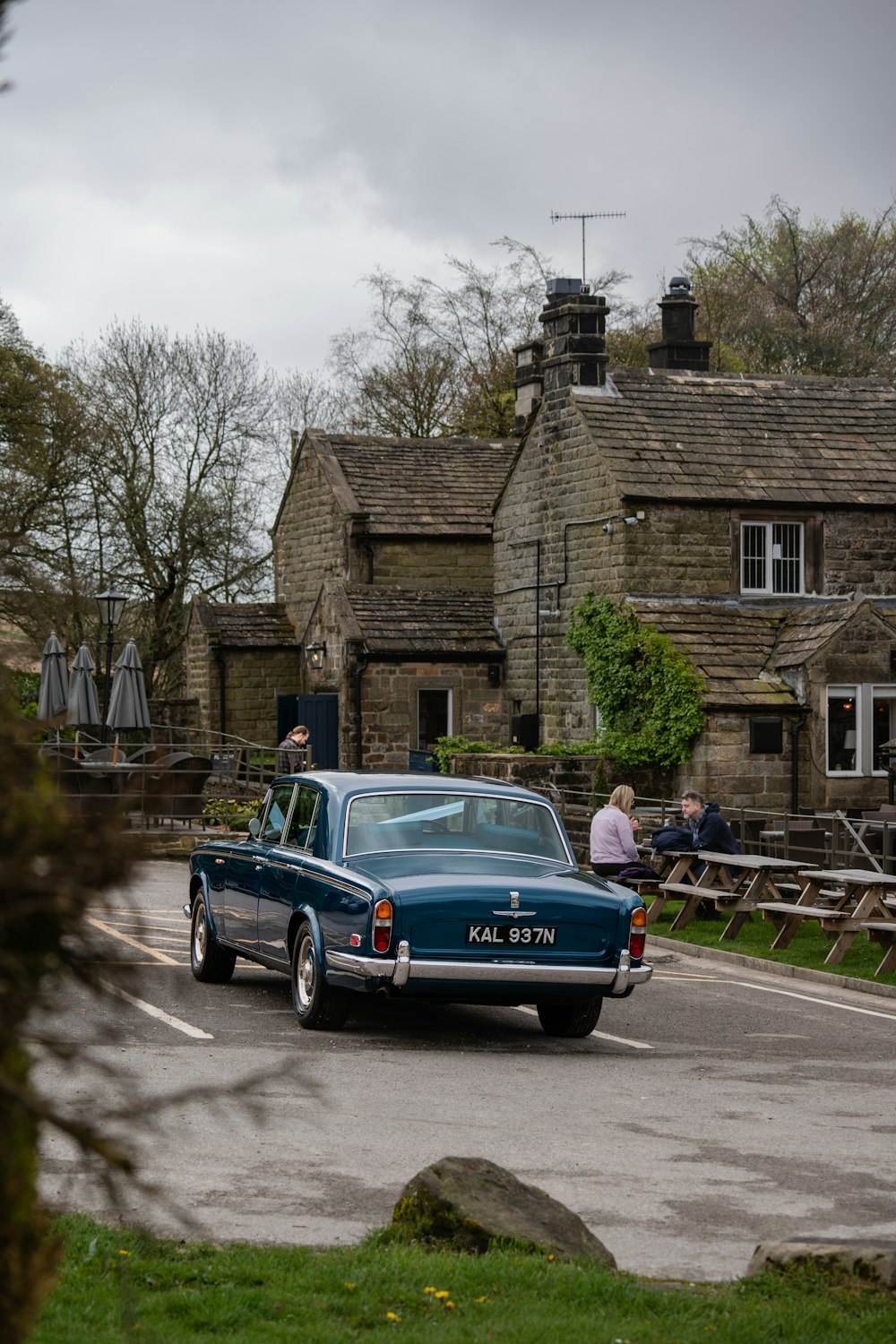 a blue car driving down a road next to a building