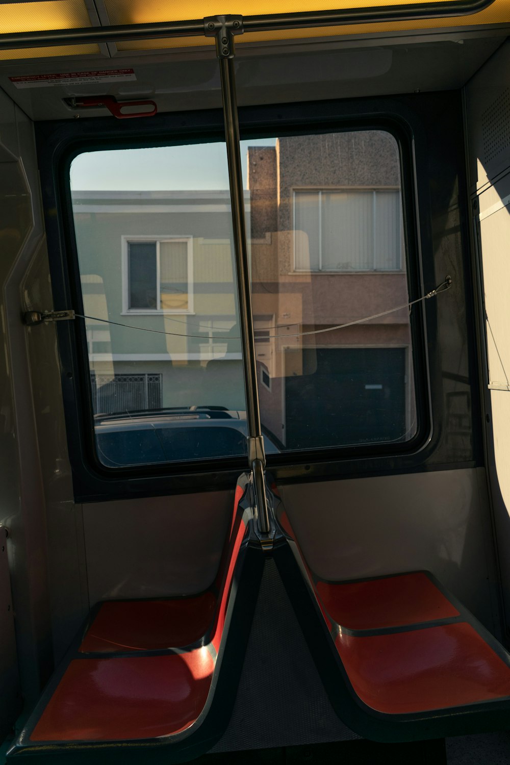 two red seats on a bus with a building in the background