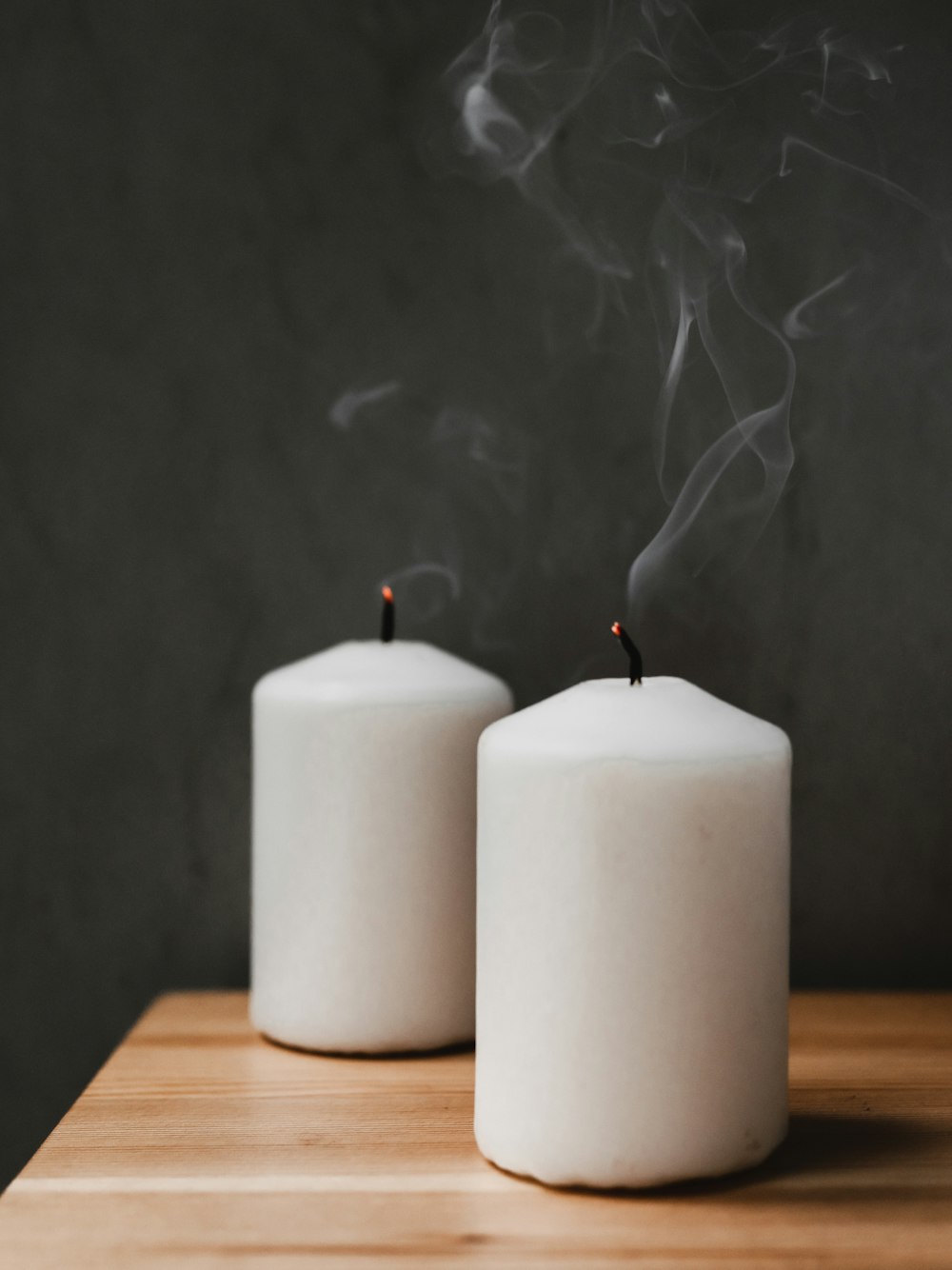 Un par de velas blancas sentadas encima de una mesa de madera
