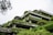 A multi-story building draped in lush green vines and shrubbery offers a harmonious blend of architecture and nature. The structure features concrete terraces and large windows, with trees and plants adorning the levels, creating a vertical garden effect.