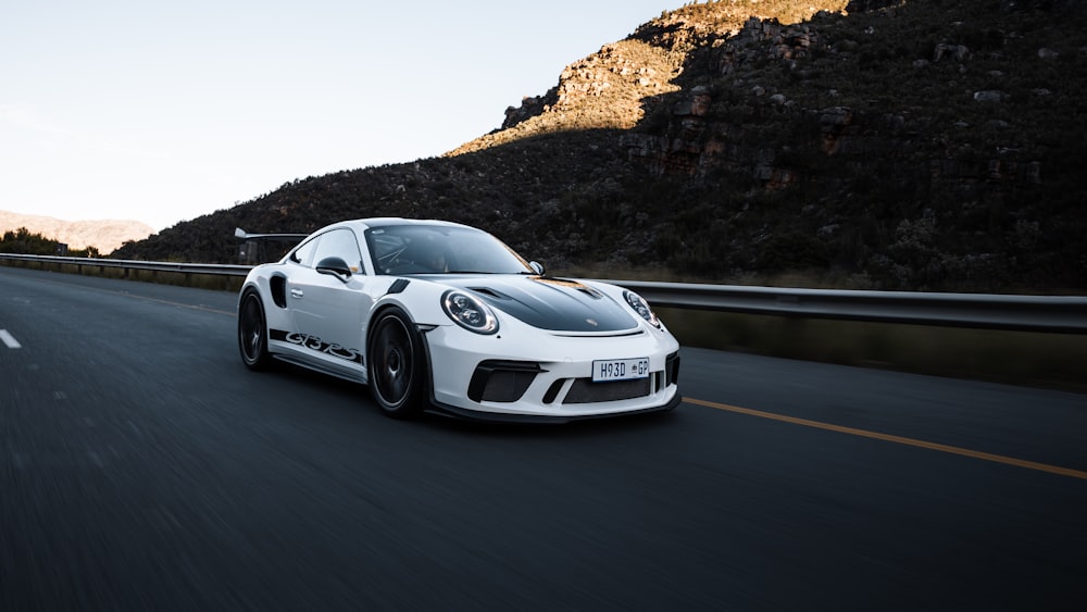 a white sports car driving down the road