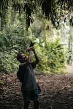 A candid shot of Bella Vixens photographing a couple in a sunlit forest.