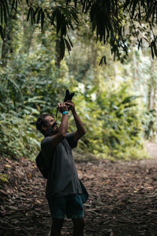 A candid shot of Bella Vixens photographing a couple in a sunlit forest.