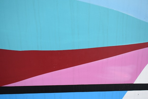 Geometric abstract artwork featuring intersecting shapes in various colors, including blue, red, pink, and black, arranged in a layered composition.