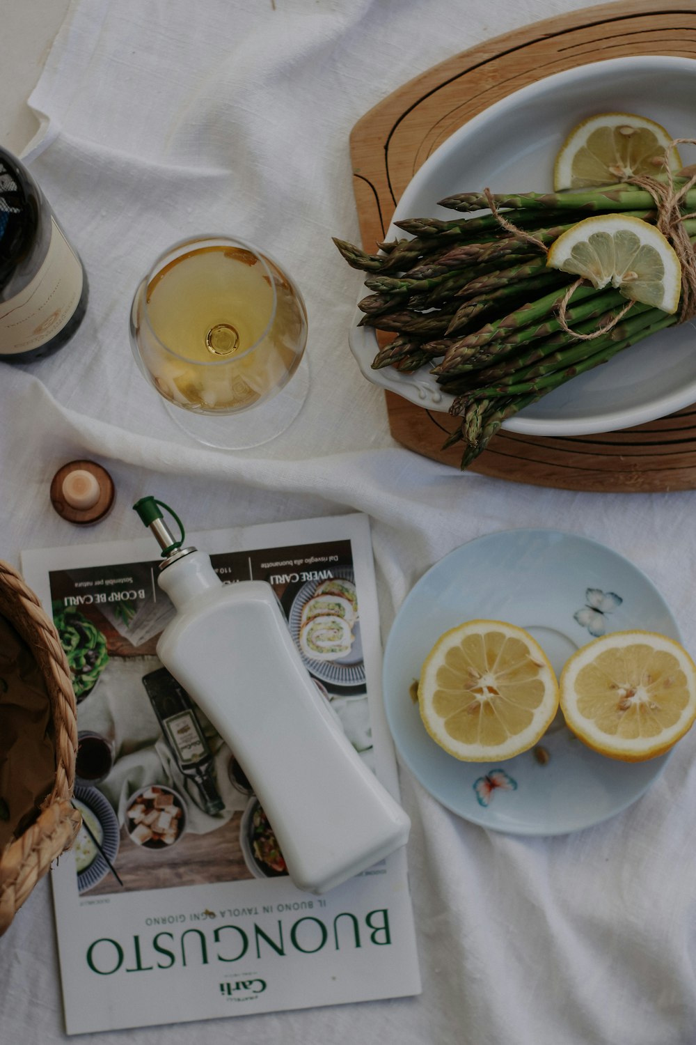 a plate of asparagus, lemons, and a bottle of wine