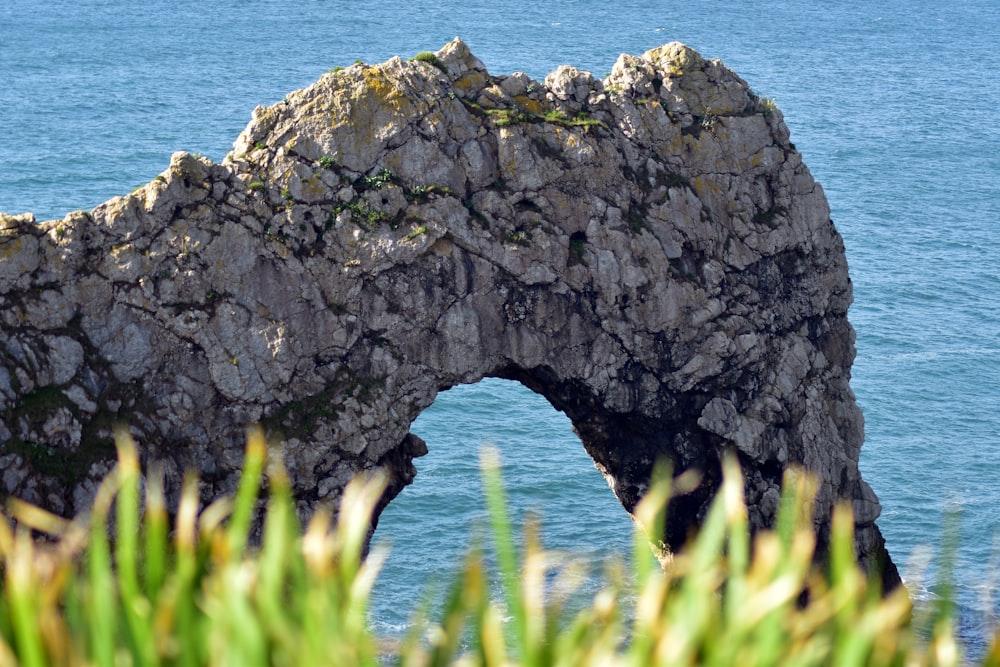 a rock arch in the middle of a body of water