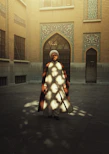 A smiling man dressed in a classic kurta-pajama set standing in a sunlit courtyard.