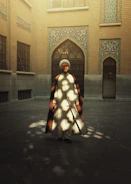 A smiling man dressed in a classic kurta-pajama set standing in a sunlit courtyard.