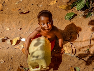 a young boy sitting on the ground holding a banana