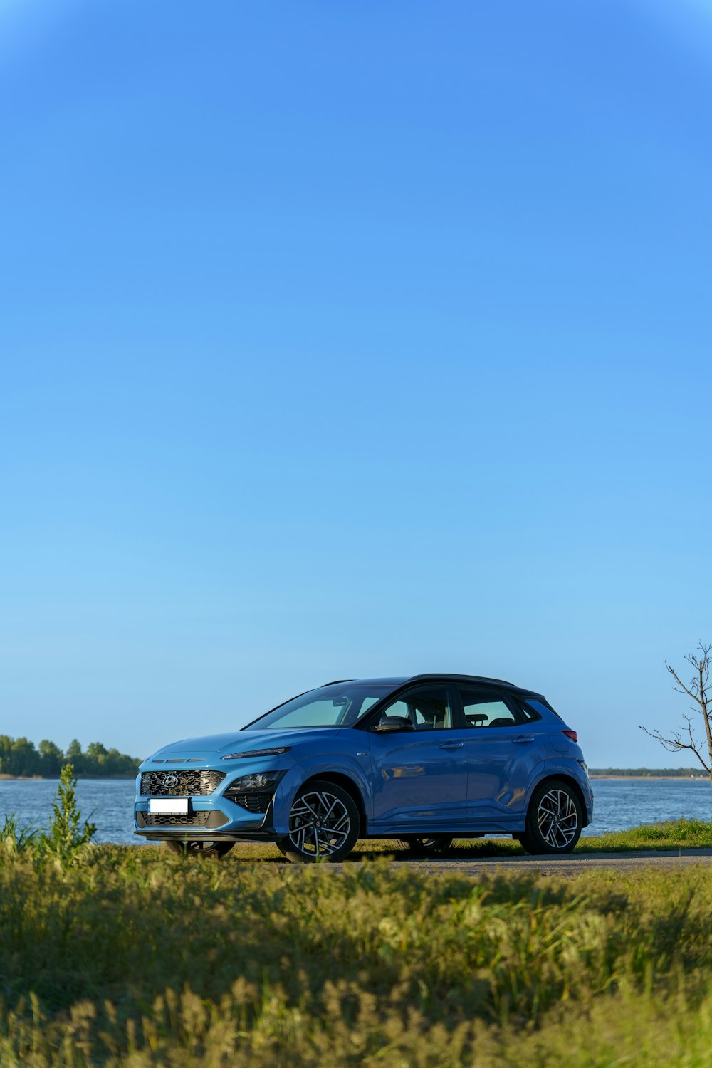 Une voiture bleue garée à côté d’un plan d’eau