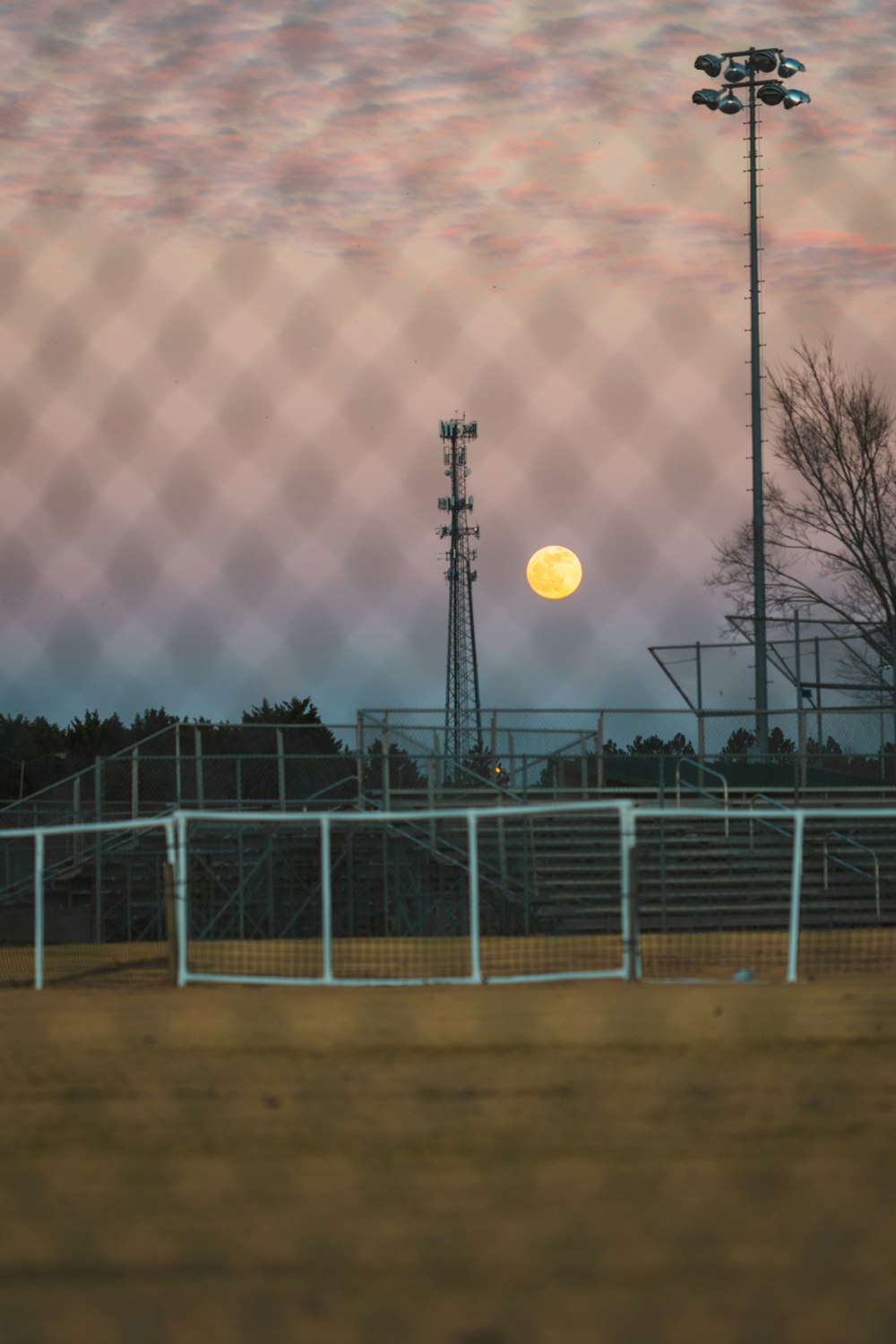a full moon is seen behind a fence