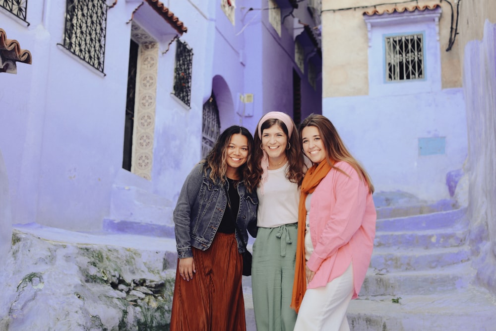 a group of women standing next to each other in front of a building