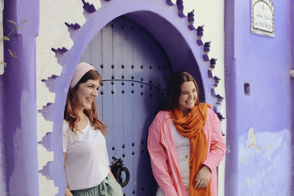 two women standing in front of a purple door