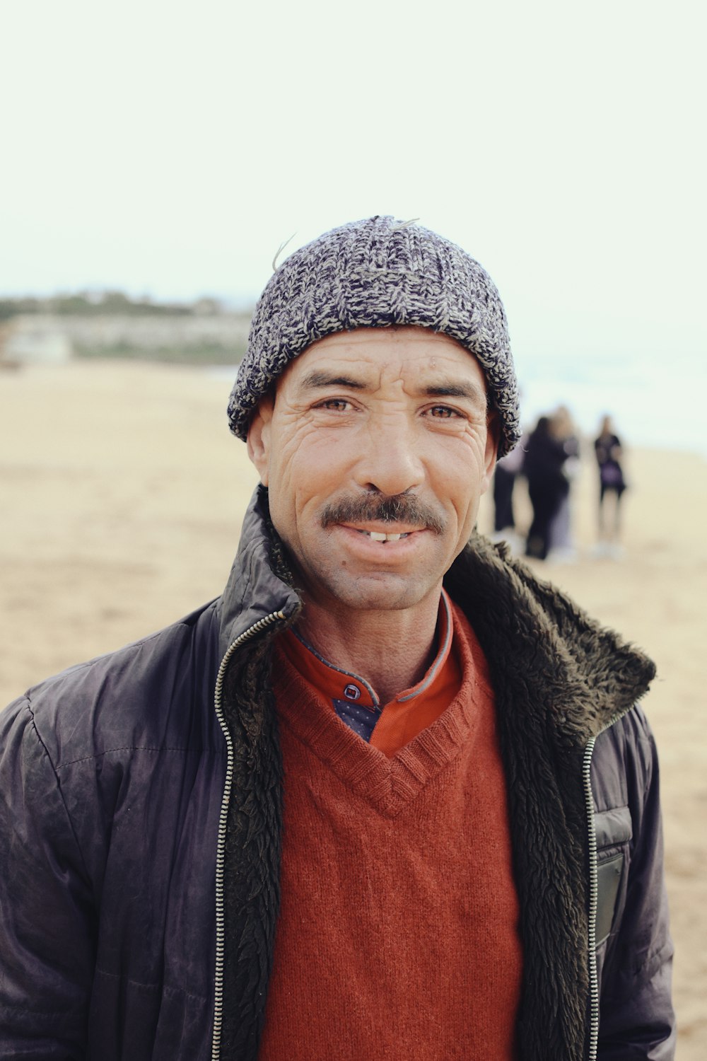 a man standing on a beach wearing a hat