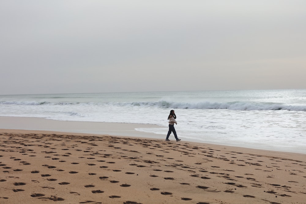 a person walking on a beach with footprints in the sand