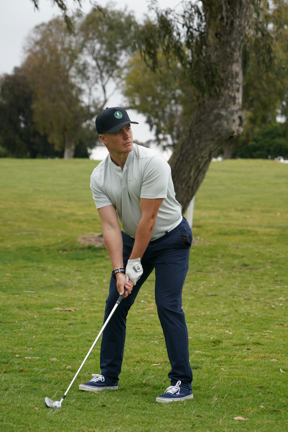 a man holding a golf club on top of a green field