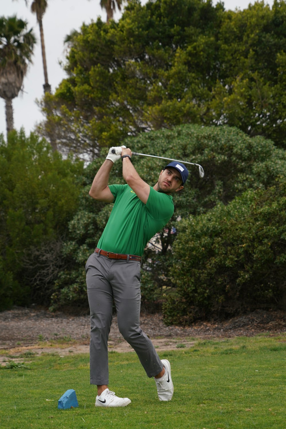 a man in a green shirt swinging a golf club
