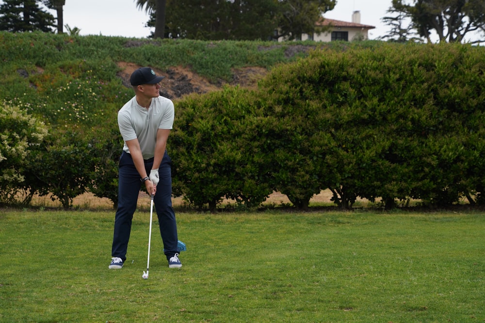 a man holding a golf club on top of a green field