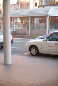A friendly taxi driver helping a passenger with luggage on a quiet street.