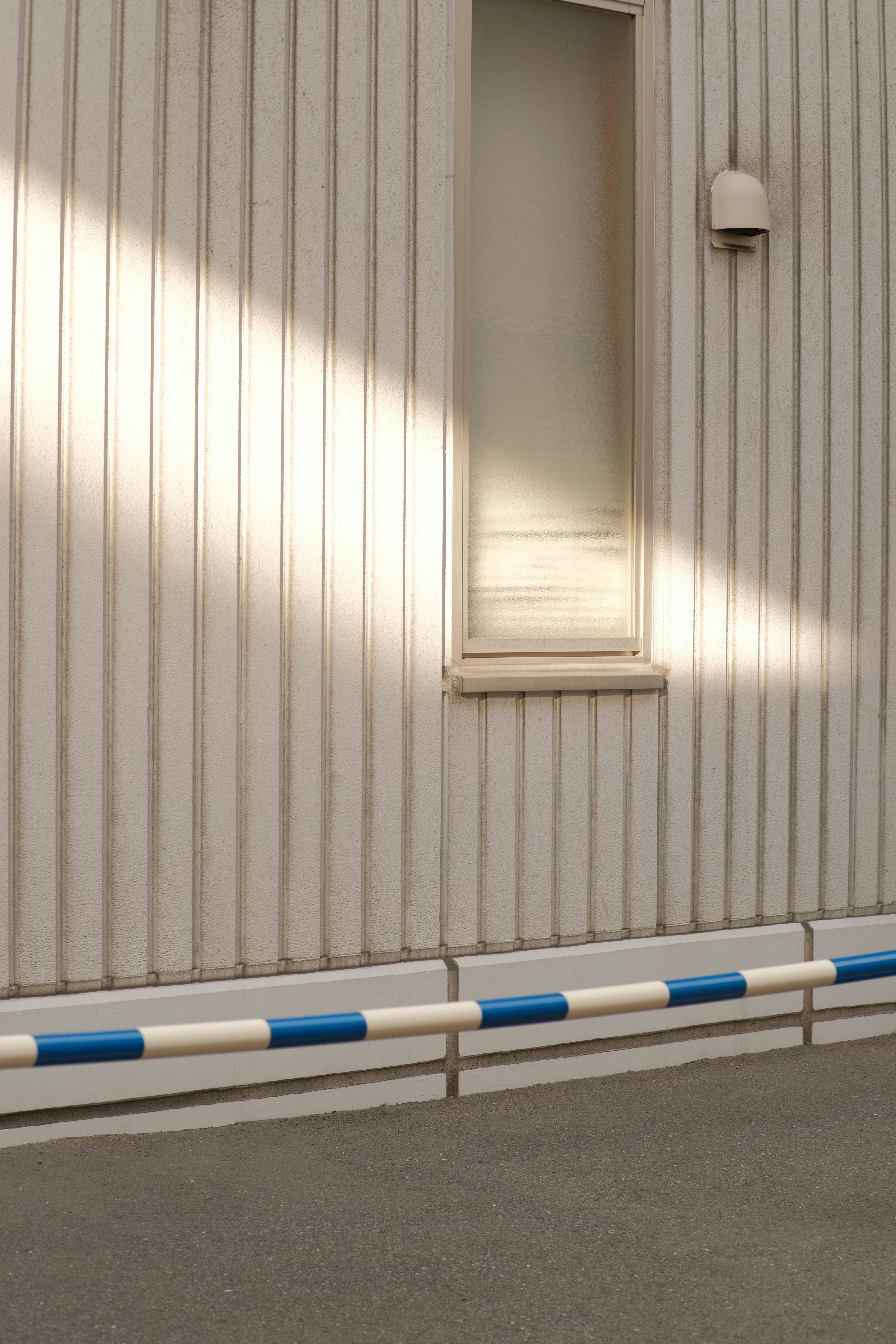 Ein weißes Gebäude mit einem Fenster und einer blau-weißen Linie
