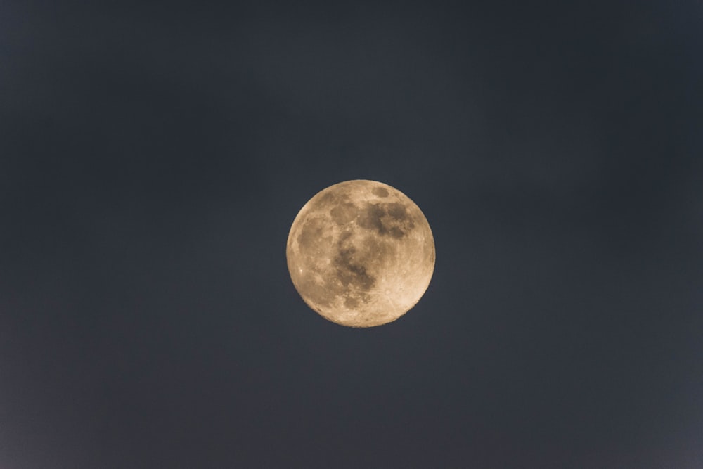 a full moon is seen in the dark sky