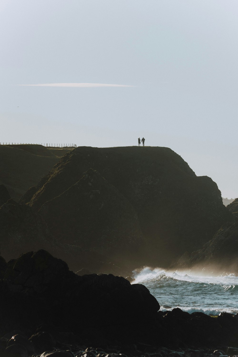 a couple of people standing on top of a cliff