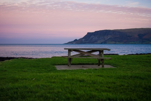 A cozy picnic table set in a lush green valley surrounded by mountains.