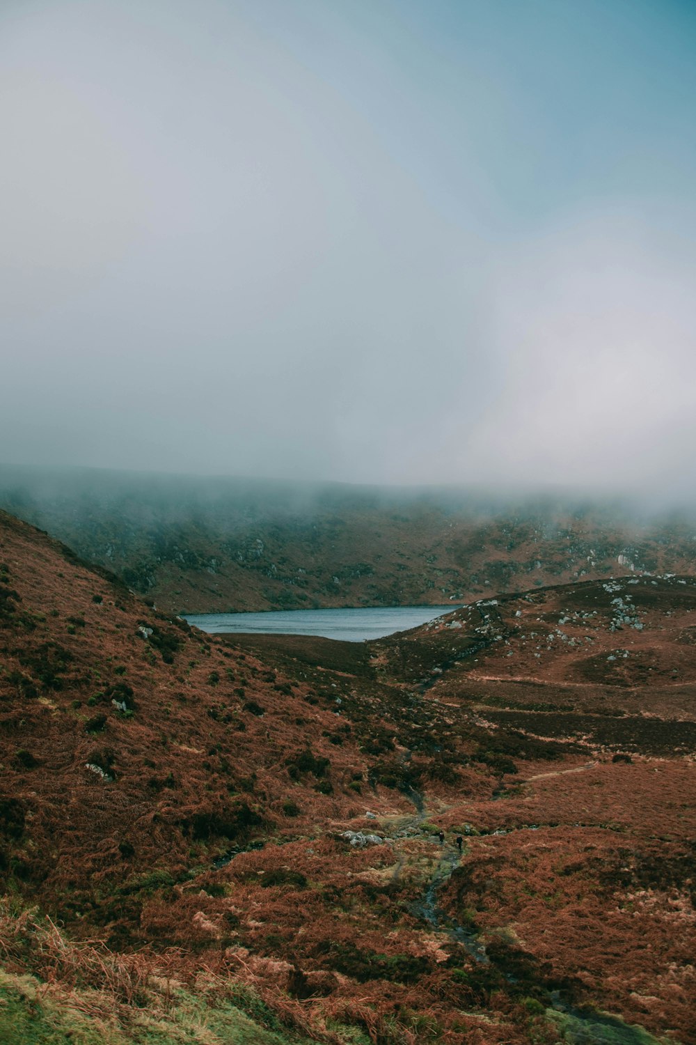 a foggy landscape with a lake in the distance