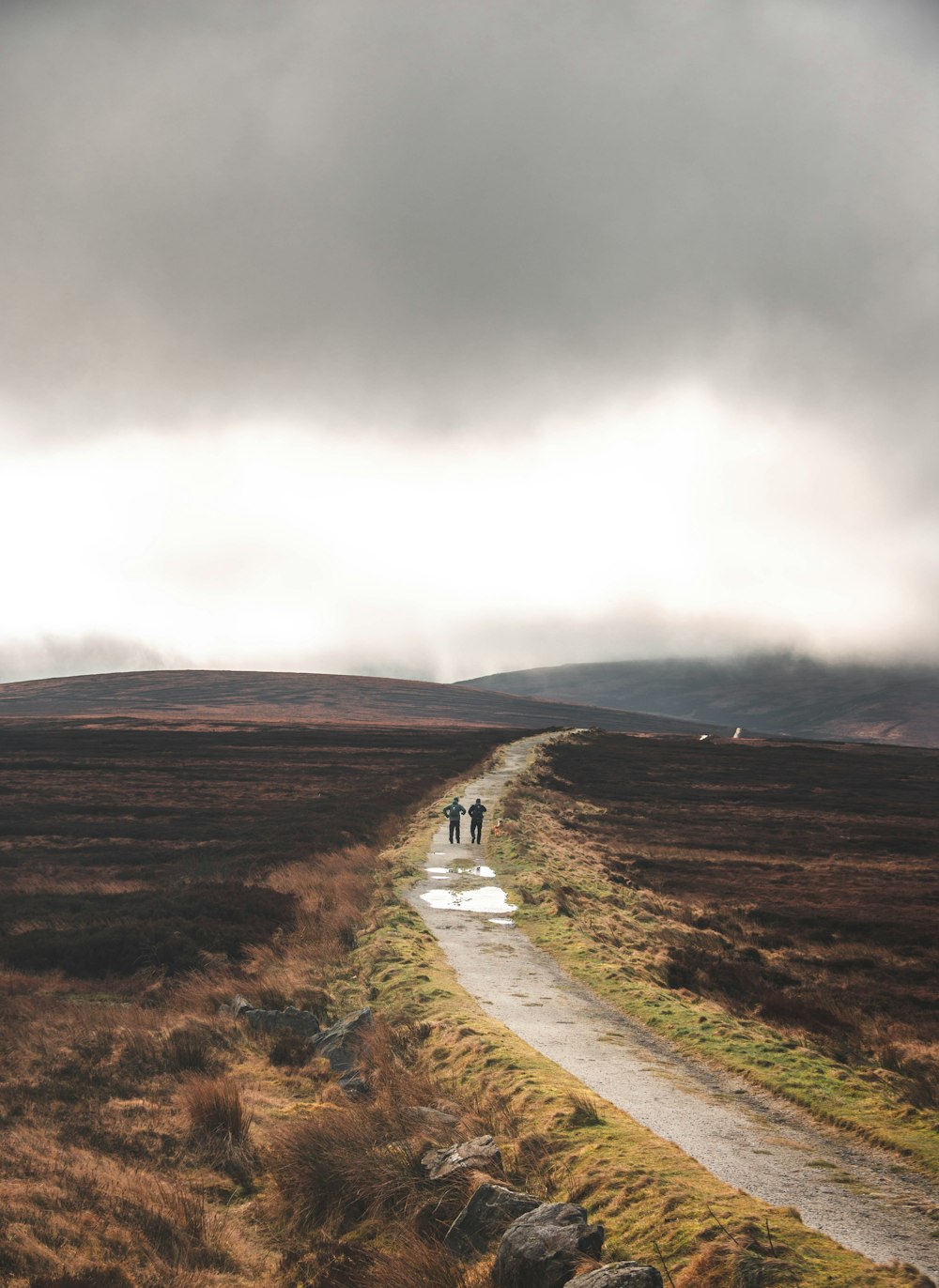 two people walking down a path in the middle of a field