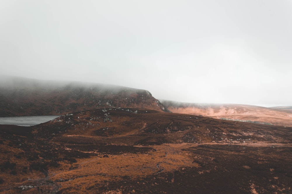 a foggy mountain with a body of water in the distance