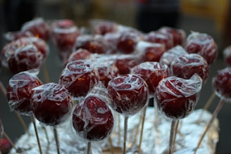 Close-up photo of a shiny red candy apple with cinnamon, glistening under warm light