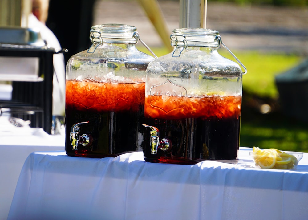 a table topped with two jars filled with liquid