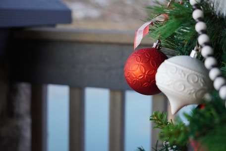 Festive resin holiday ornaments hanging on a rustic wooden branch.