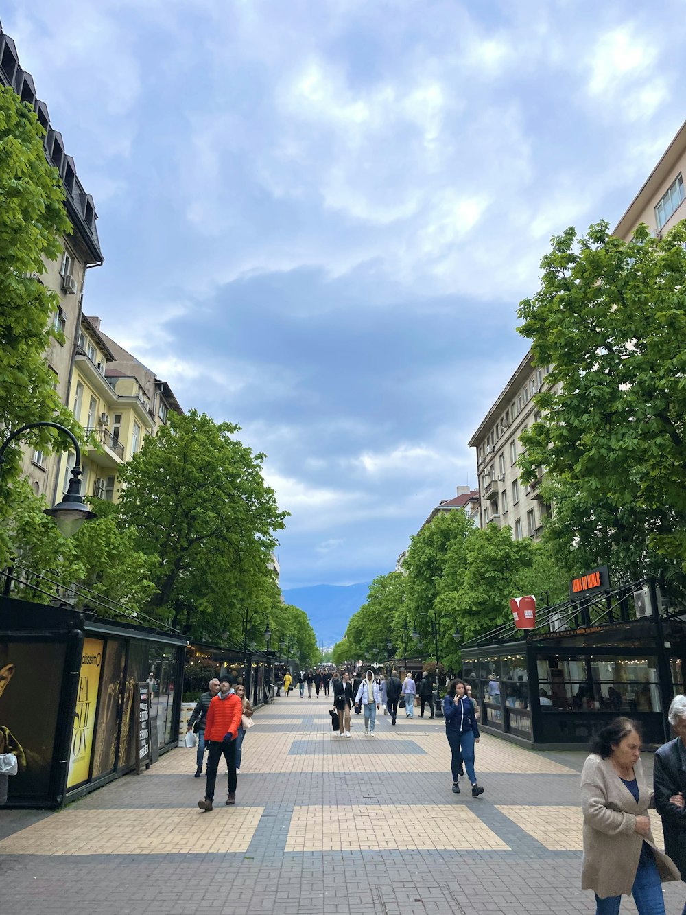 a group of people walking down a street next to tall buildings