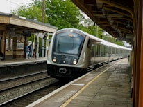 A sleek train arriving at a modern station under clear skies.