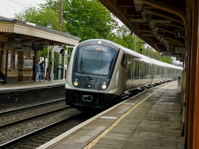 A sleek train arriving at a modern station under clear skies.